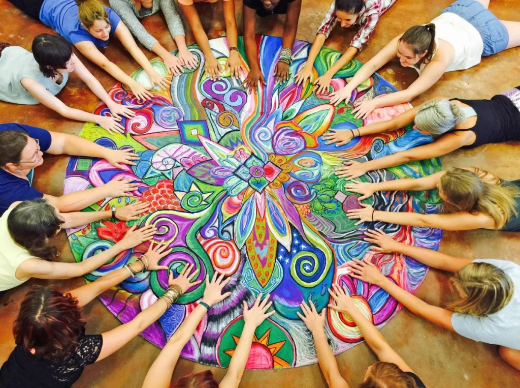 Several children putting their hands towards the center of a rangoli 