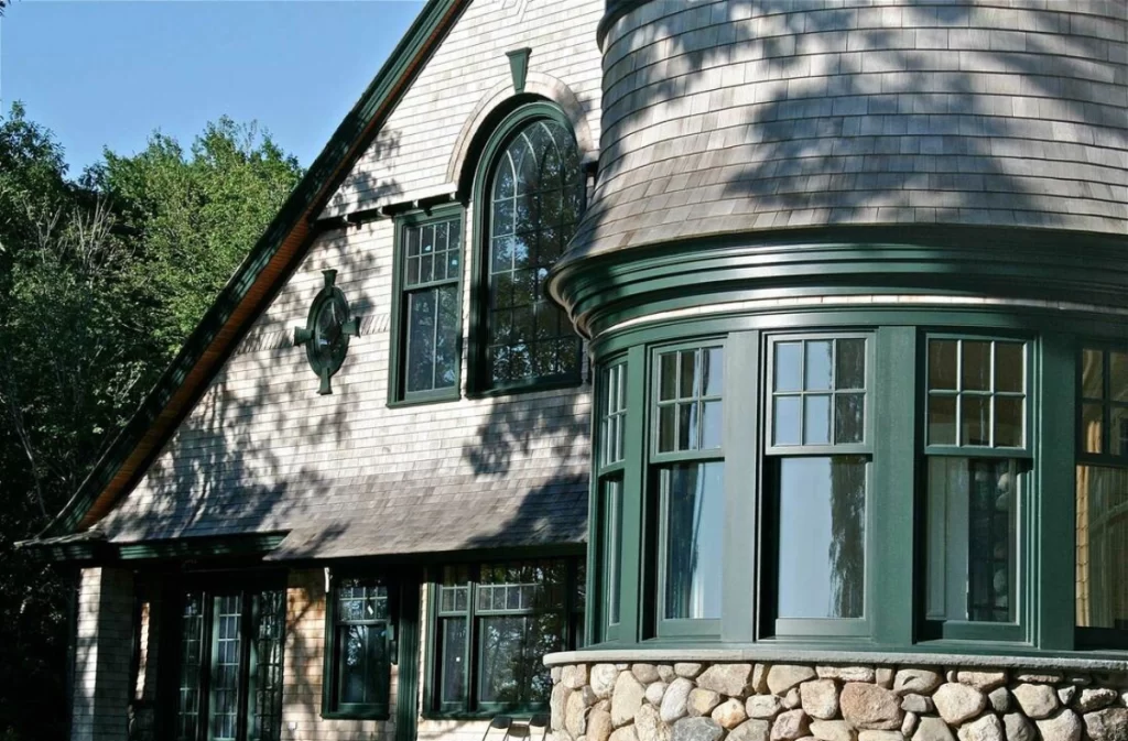 A shingle style house with many windows of different shapes and sizes 