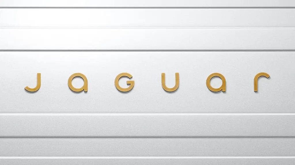 Minimalistic text logo of 'Jaguar' in gold letters on a metallic silver background with horizontal grooves, evoking a sleek and modern design aesthetic.