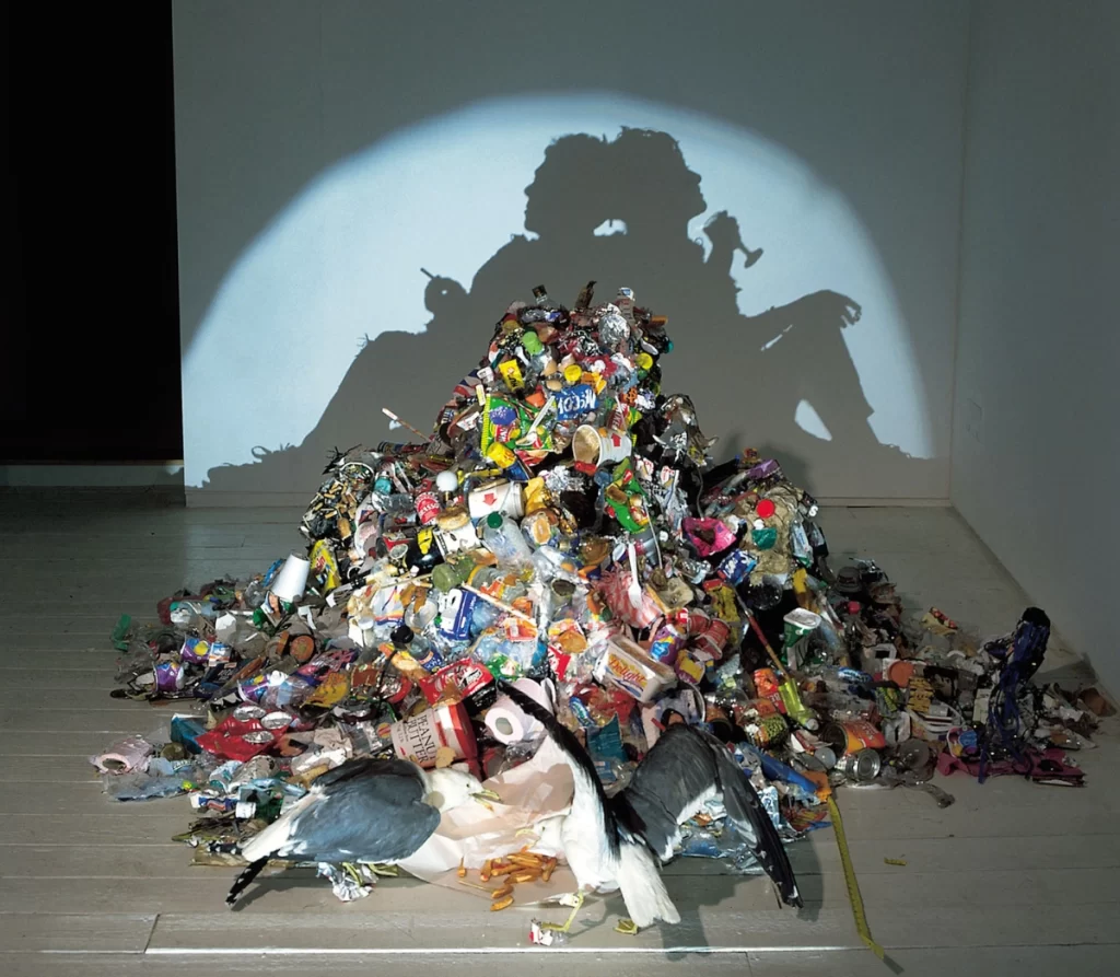 Trash arranged to make a shadow art of two people 