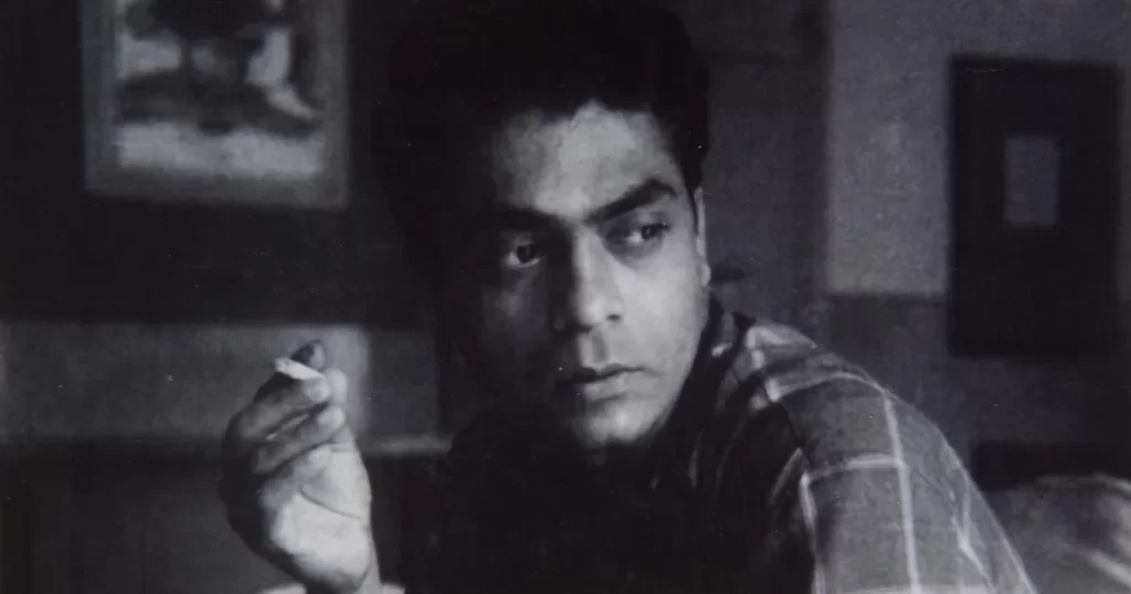 A black-and-white portrait of Vasudeo S. Gaitonde, an Indian modernist artist, looking contemplative with a cigarette in his hand. The setting is minimal, with a soft-focus background, emphasizing his thoughtful expression and artistic persona. ​​