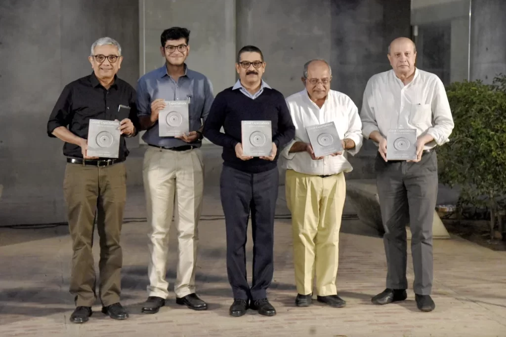 Five individuals, Barjor Mehta, Karan S. Gandhi, Ram Prasad Akkisetti, Tridip Suhrud, and Bimal Patel, standing side by side, each holding a copy of Great Expectations: Notes to an Architect by Christopher Benninger, during the book launch event at CEPT University. The backdrop is minimal with greenery visible on the side.