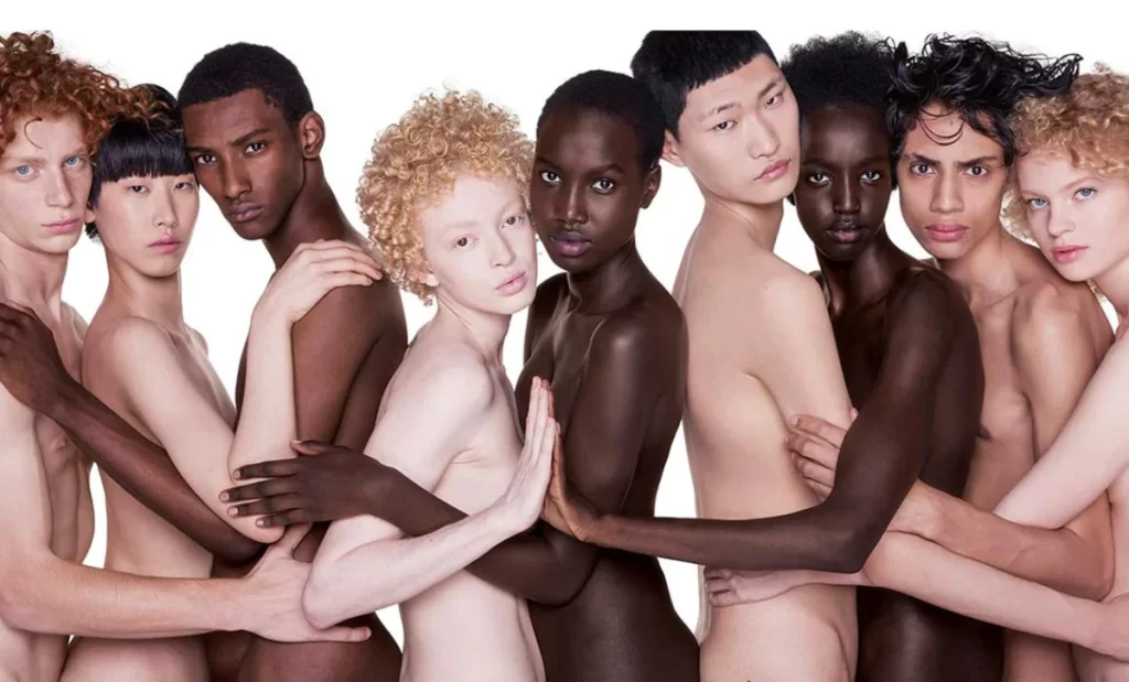 A group of naked people of different multi-racial ethnicities hugging each other 